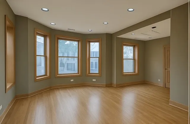 a view of an empty room with a window and wooden floor