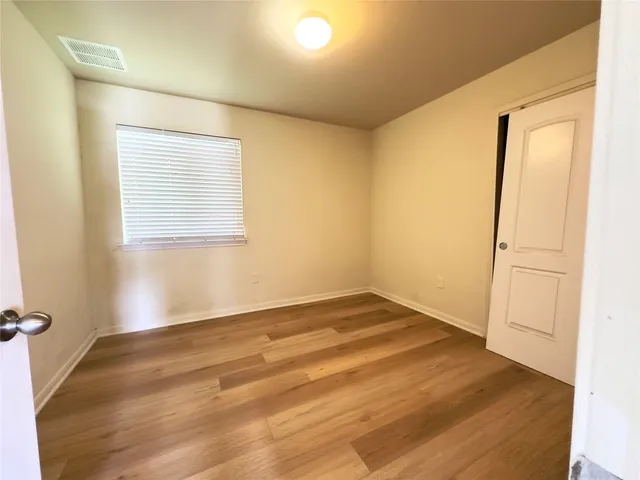 an empty room with wooden floor ceiling fan and windows