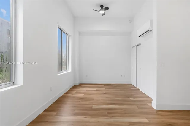 a view of empty room with wooden floor and fan