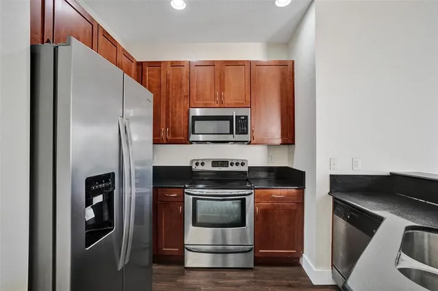 a kitchen with stainless steel appliances kitchen island granite countertop a stove a sink and a refrigerator
