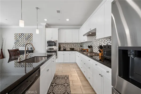 a large kitchen with stainless steel appliances kitchen island granite countertop a sink stove and refrigerator