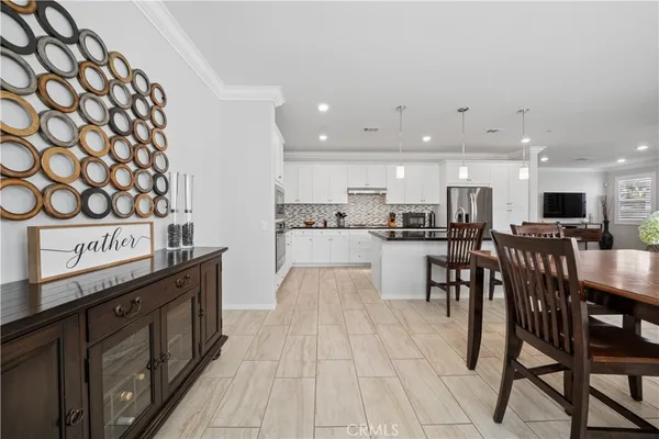 a kitchen with stainless steel appliances kitchen island granite countertop a table chairs sink and cabinets