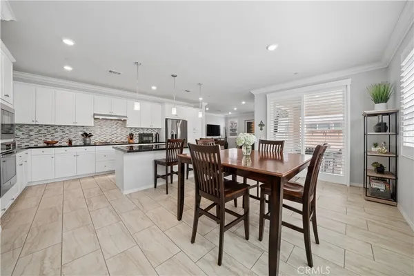 a kitchen with stainless steel appliances kitchen island granite countertop a table chairs sink and cabinets