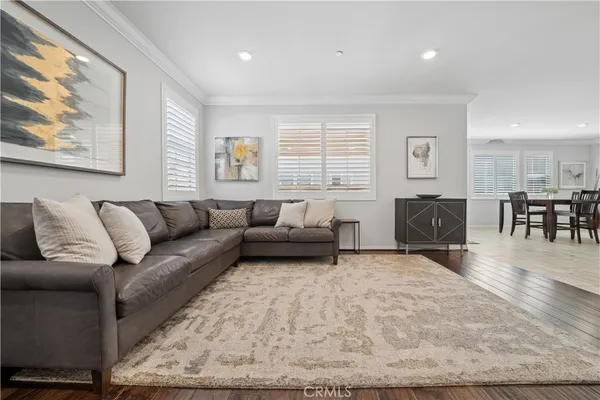 a living room with furniture and a dining table with wooden floor