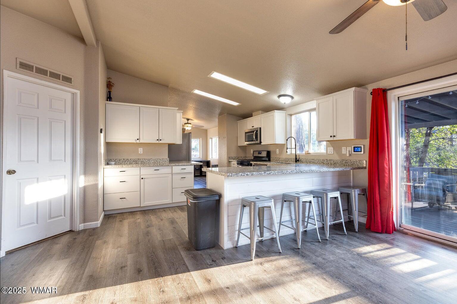 430 Timber Ridge Loop Show Low, AZ 85901 - Photo 6 of 27 a kitchen with stainless steel appliances kitchen island granite countertop a refrigerator a stove a sink dishwasher and white cabinets with wooden floor
