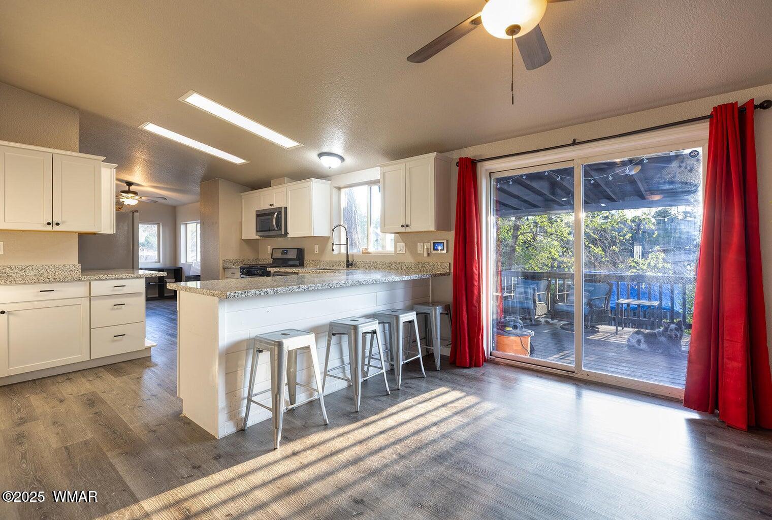 430 Timber Ridge Loop Show Low, AZ 85901 - Photo 7 of 27 a kitchen with stainless steel appliances granite countertop a stove top oven a sink dishwasher a refrigerator and white cabinets with wooden floor
