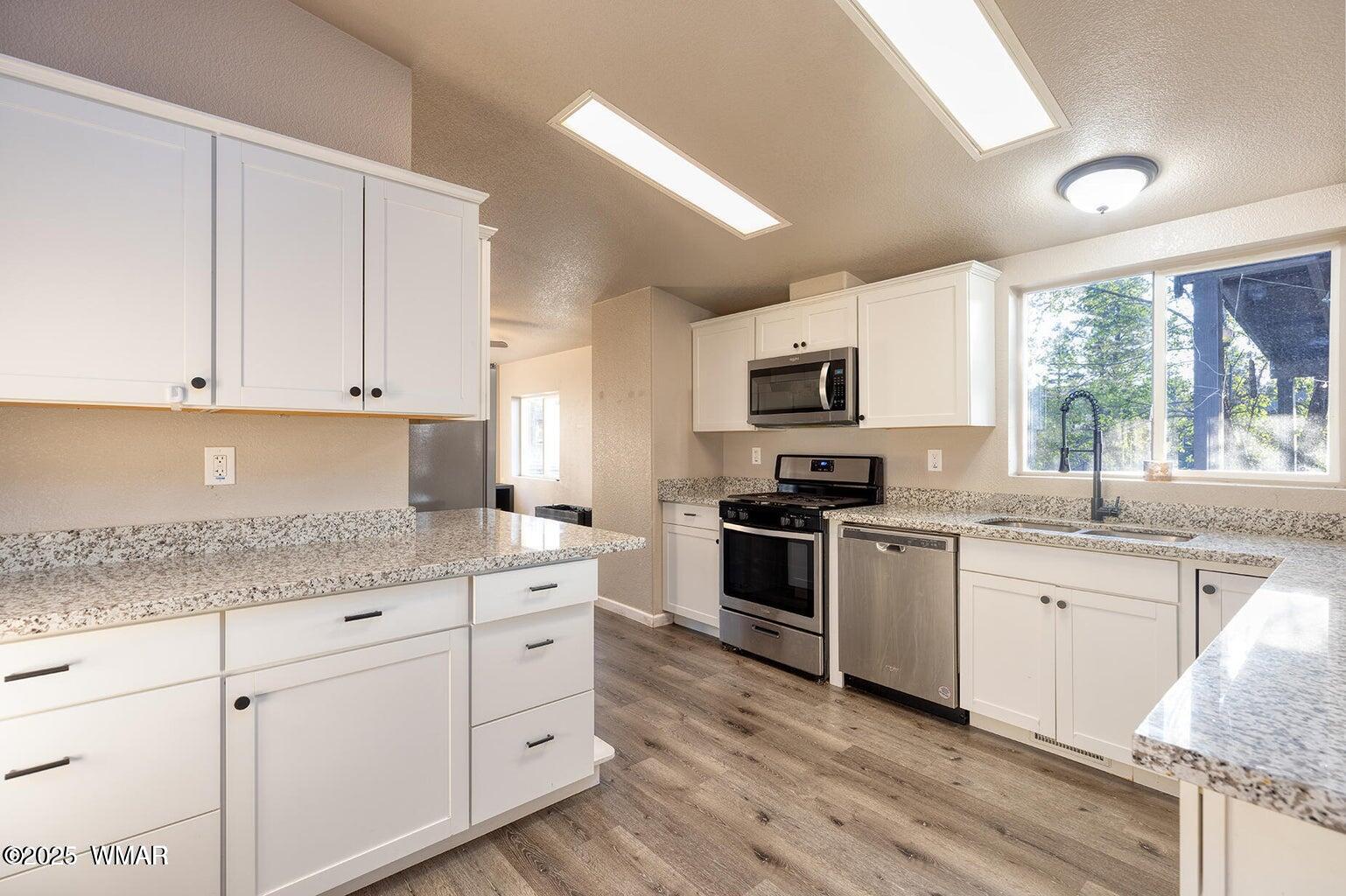 430 Timber Ridge Loop Show Low, AZ 85901 - Photo 9 of 27 a kitchen with granite countertop white cabinets sink and stainless steel appliances