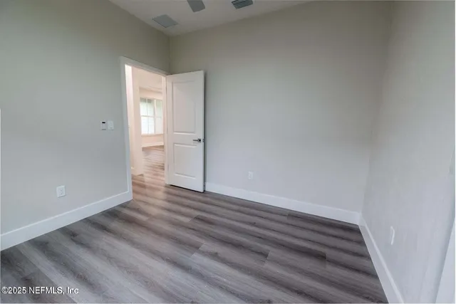 a view of a hallway with wooden floor and a bathroom