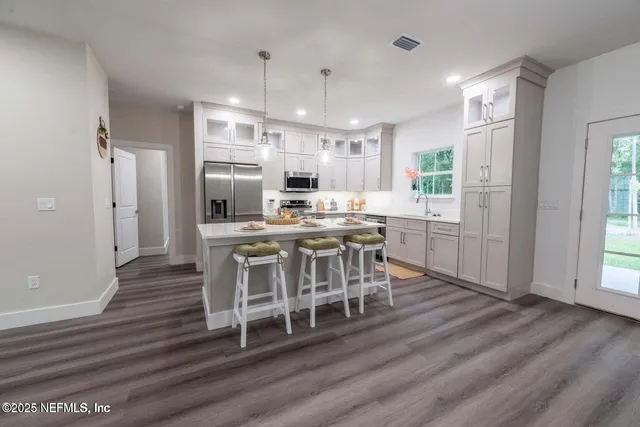 a kitchen with stainless steel appliances a dining table chairs stove microwave and cabinets