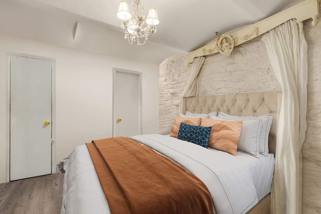 517 East 87th Street, Unit TRIPLEX Manhattan, NY 10128 - Photo 20 of 24 a bedroom with a bed and a chandelier