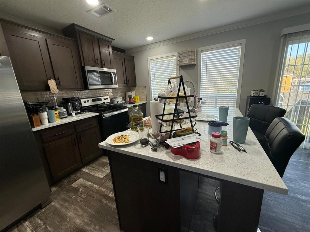 17151 Lemon Street Spring Hill, FL 34610 - Photo 14 of 18 a kitchen with stainless steel appliances kitchen island granite countertop a sink dishwasher stove refrigerator and cabinets