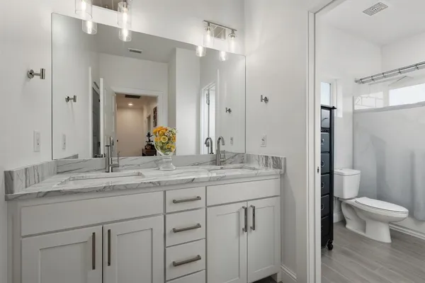 a bathroom with a granite countertop sink a toilet and a mirror