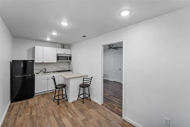 a kitchen with stainless steel appliances a refrigerator a stove a sink and white cabinets with wooden floor