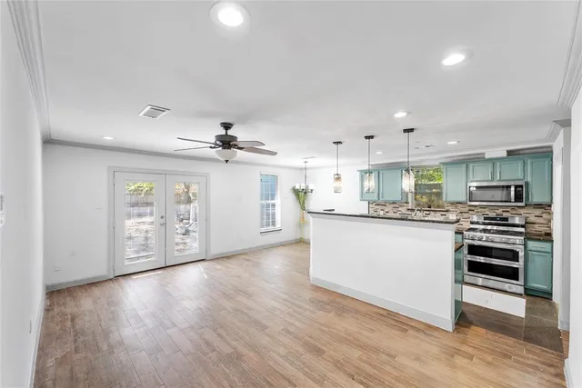 a kitchen with stainless steel appliances granite countertop a stove top oven a sink with wooden floors