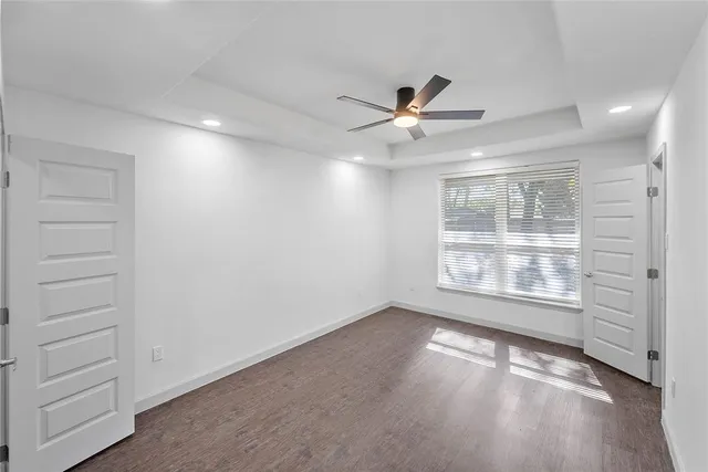 a view of an empty room with a window and wooden floor