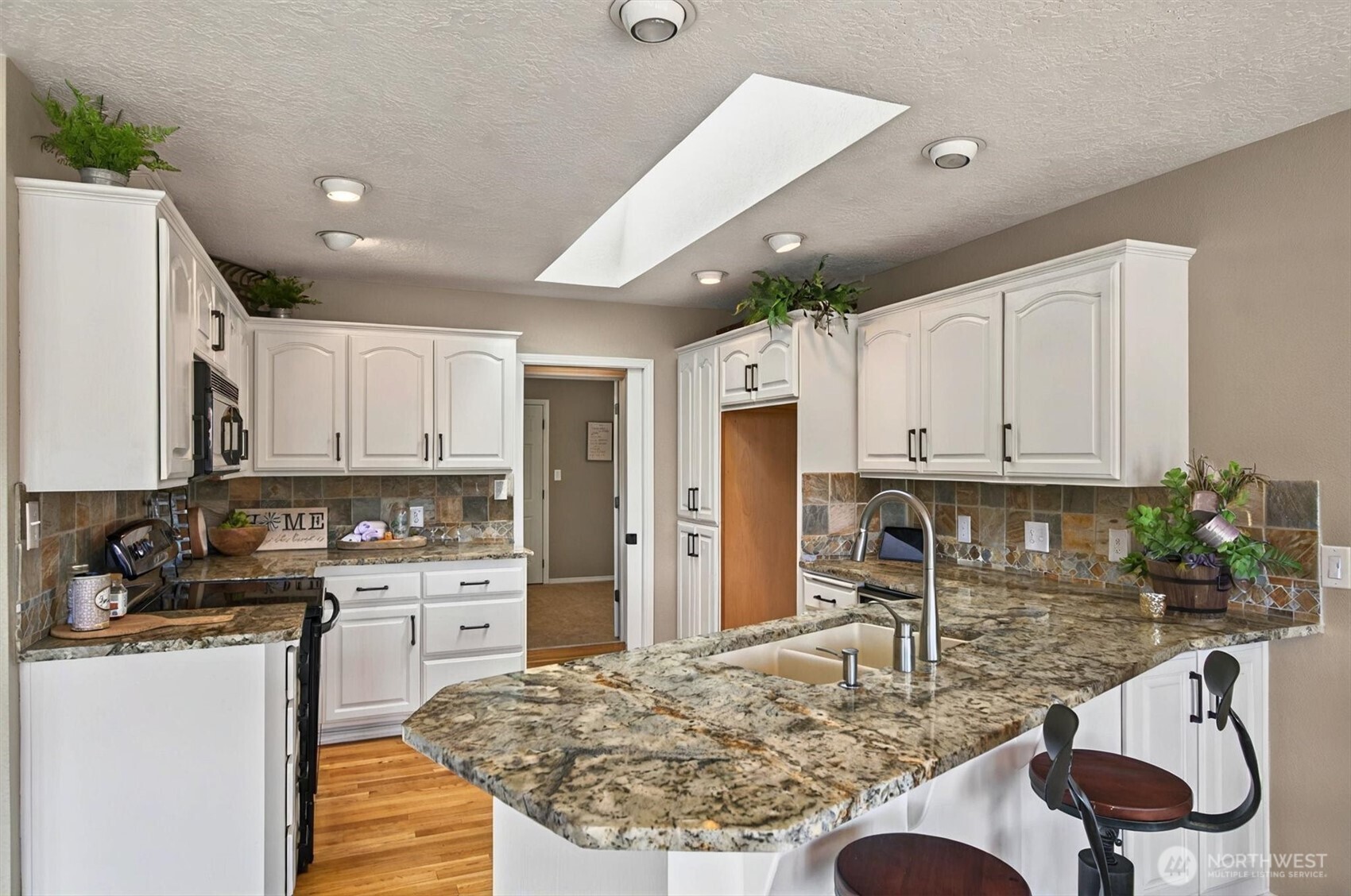 293 Highway 409 Cathlamet, WA 98612 - Photo 12 of 39 a kitchen with granite countertop a stove and white cabinets