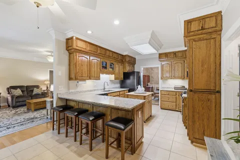 a kitchen with stainless steel appliances granite countertop a refrigerator a stove a sink a dining table and chairs with wooden floor