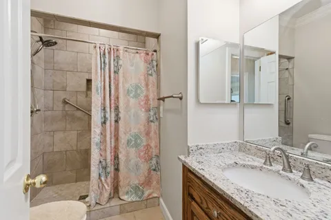a bathroom with a granite countertop shower sink vanity and toilet