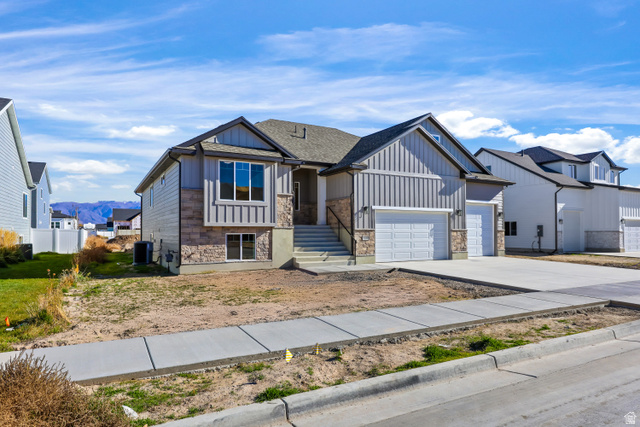 1139 South 4475 West West Point, UT 84015 - Photo 3 of 33 View of front of house featuring concrete driveway, a mountain view, stone siding, board and batten siding, and a garage