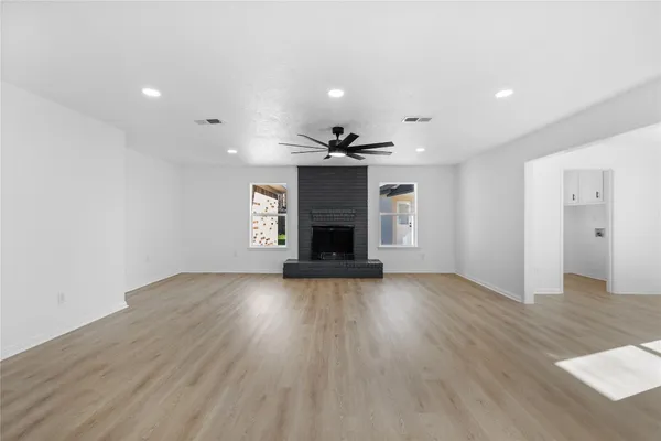 an empty room with wooden floor fireplace and windows