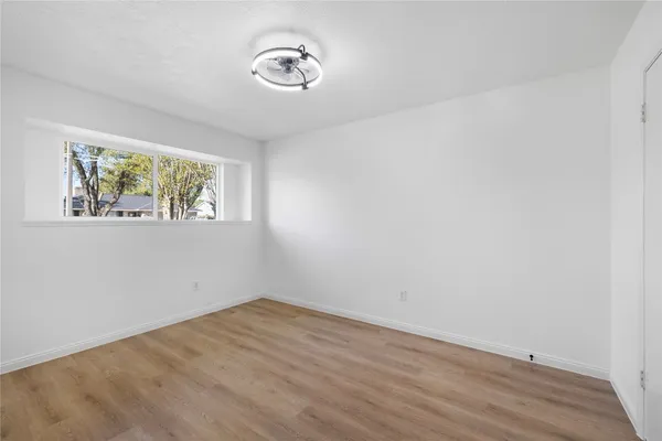 a view of empty room with window and wooden floor