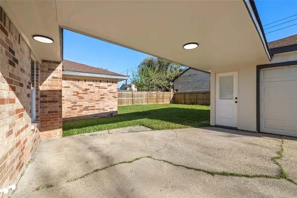 a view of a backyard with brick wall and plants