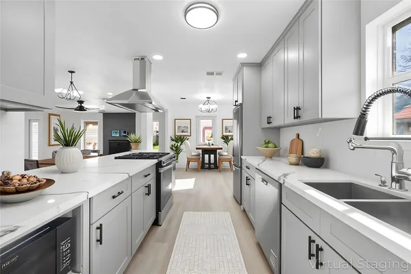 a kitchen with stainless steel appliances granite countertop a sink dishwasher stove and white cabinets with wooden floor