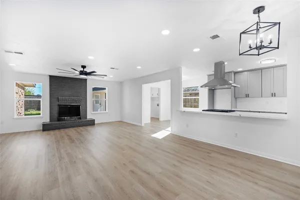 an empty room with wooden floor fireplace and windows