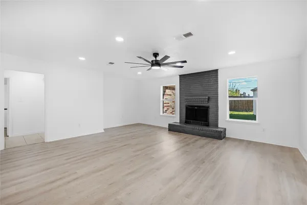 an empty room with wooden floor a fireplace and windows