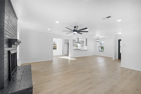 an empty room with wooden floor fireplace and windows