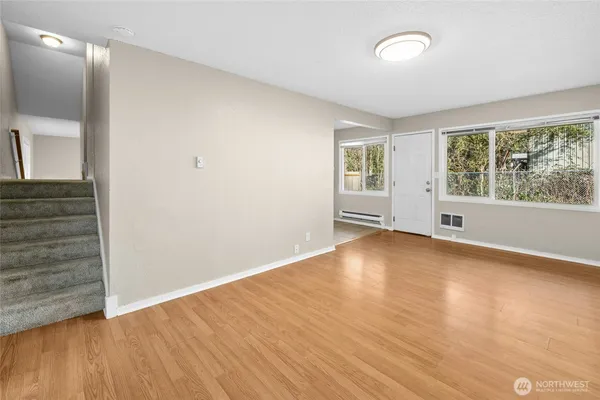 an empty room with wooden floor and windows