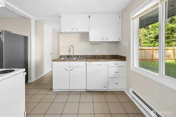 a kitchen with white cabinets appliances a sink and a window
