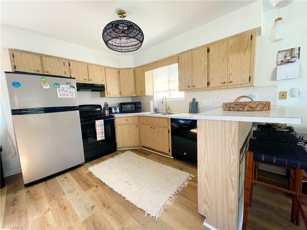 4811 Gary Road Bonita Springs, FL 34134 - Photo 19 of 35 Kitchen featuring light countertops, black appliances, light brown cabinetry, light wood-type flooring, and a peninsula