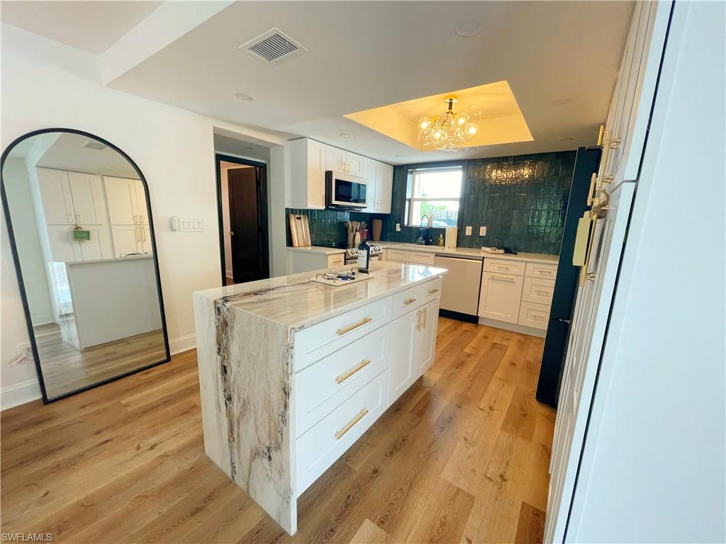 4811 Gary Road Bonita Springs, FL 34134 - Photo 26 of 35 Kitchen featuring white cabinetry, a raised ceiling, light stone countertops, dishwasher, and light wood-style floors