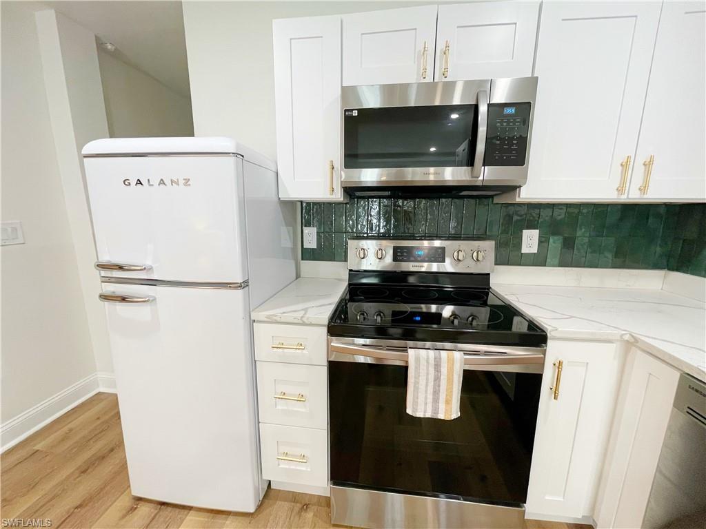 4811 Gary Road Bonita Springs, FL 34134 - Photo 28 of 35 Kitchen with stainless steel appliances, white cabinetry, tasteful backsplash, and light stone counters