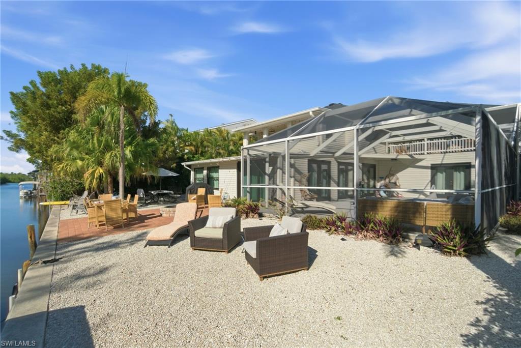 4811 Gary Road Bonita Springs, FL 34134 - Photo 9 of 35 Back of property featuring a sunroom, a patio area, a lanai, a hot tub, and an outdoor hangout area