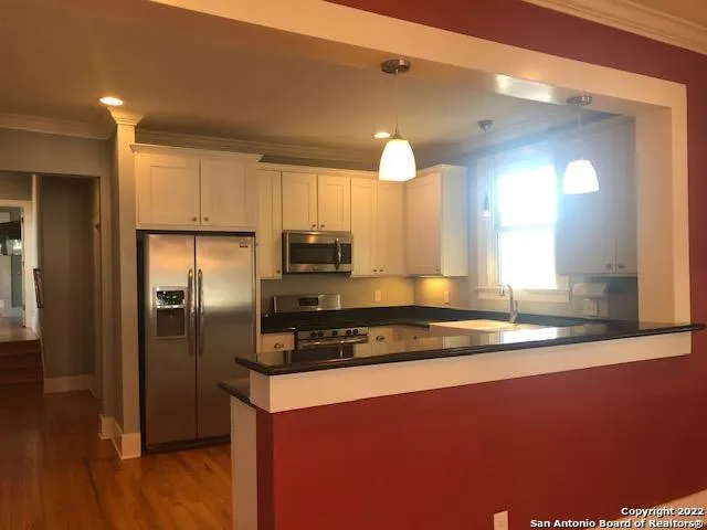 a kitchen with stainless steel appliances granite countertop a refrigerator a stove and a sink with wooden floor