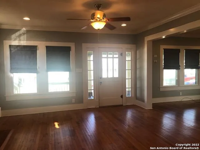 a view of an empty room with wooden floor and a window