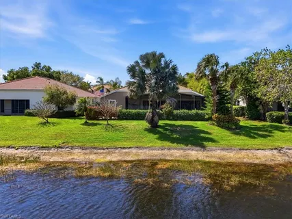 a view of a house with a big yard and palm trees