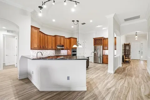 a large kitchen with stainless steel appliances granite countertop a stove a refrigerator a oven and a wooden cabinets