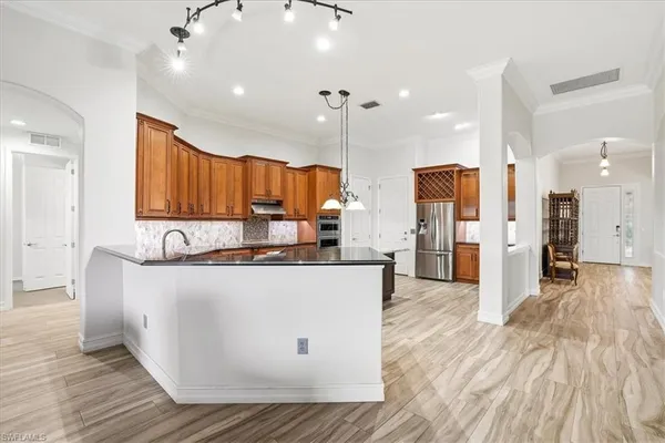 a large kitchen with stainless steel appliances granite countertop a stove a refrigerator a oven and a wooden cabinets
