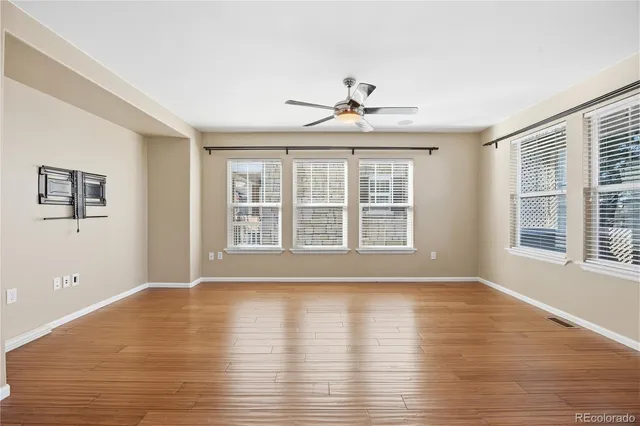 a view of an empty room with a kitchen and wooden floor