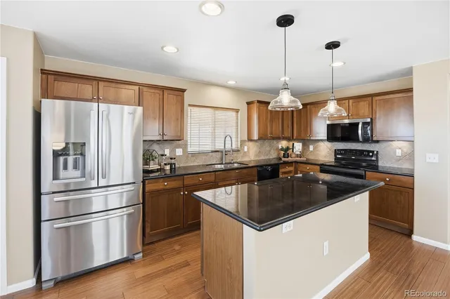 a kitchen with stainless steel appliances granite countertop a sink stove microwave and refrigerator