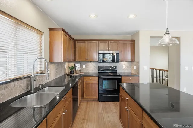 a kitchen with stainless steel appliances granite countertop a sink a stove and a wooden floor