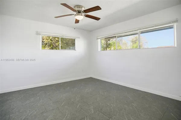 an empty room with a window and ceiling fan