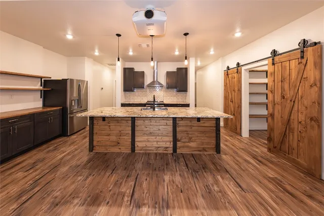 a kitchen with stainless steel appliances kitchen island granite countertop a stove a refrigerator and a wooden floors