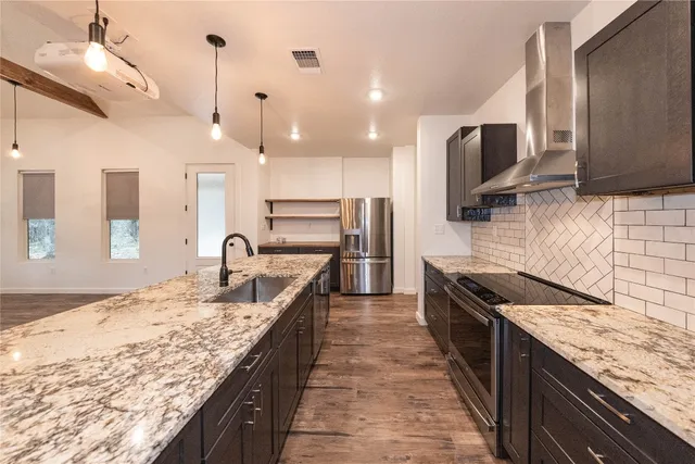 a kitchen with stainless steel appliances granite countertop a sink a stove and a wooden floors