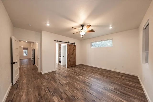 a view of an empty room with wooden floor and a ceiling fan