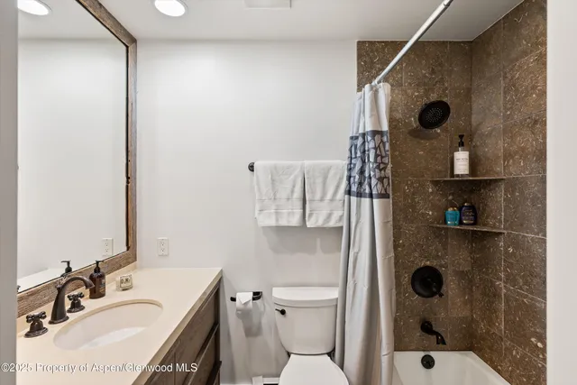 a bathroom with a granite countertop sink a toilet and shower