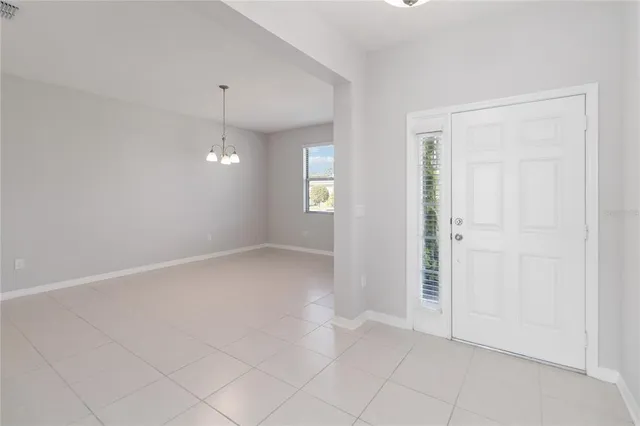 an empty room with chandelier fan and windows